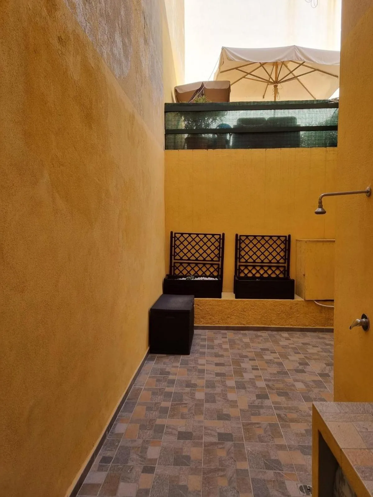 Bilocale Conti — Cortile con tavolo, sedie e doccia esterna